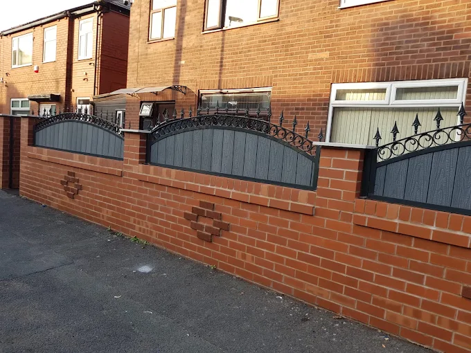 Grey boundary panels with decorative metalwork above a brick wall